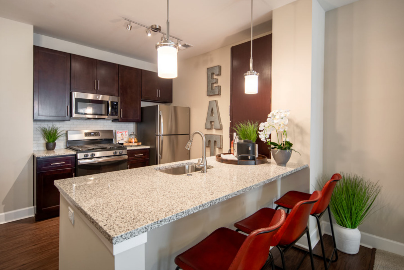 A modern kitchen at Enclave at Box Hill with sleek granite counters & shiny stainless steel appliances.