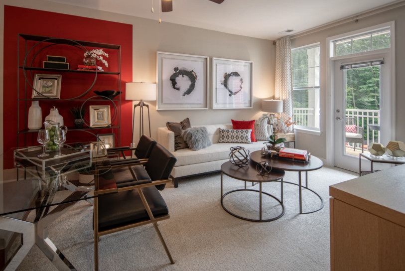 Living room with vibrant red accent walls & stylish white furniture. A luxury feature of Enclave at Box Hill's apartments.